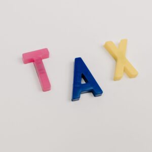 Colorful plastic letters spelling tax on a clean white background.